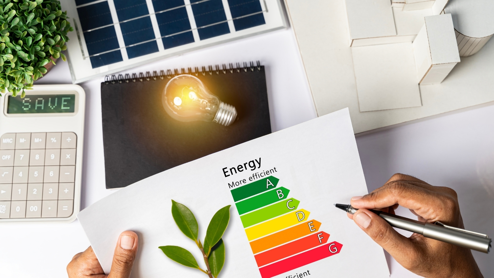 Mesa de trabajo con una etiqueta de eficiencia energética, una calculadora y una placa solar